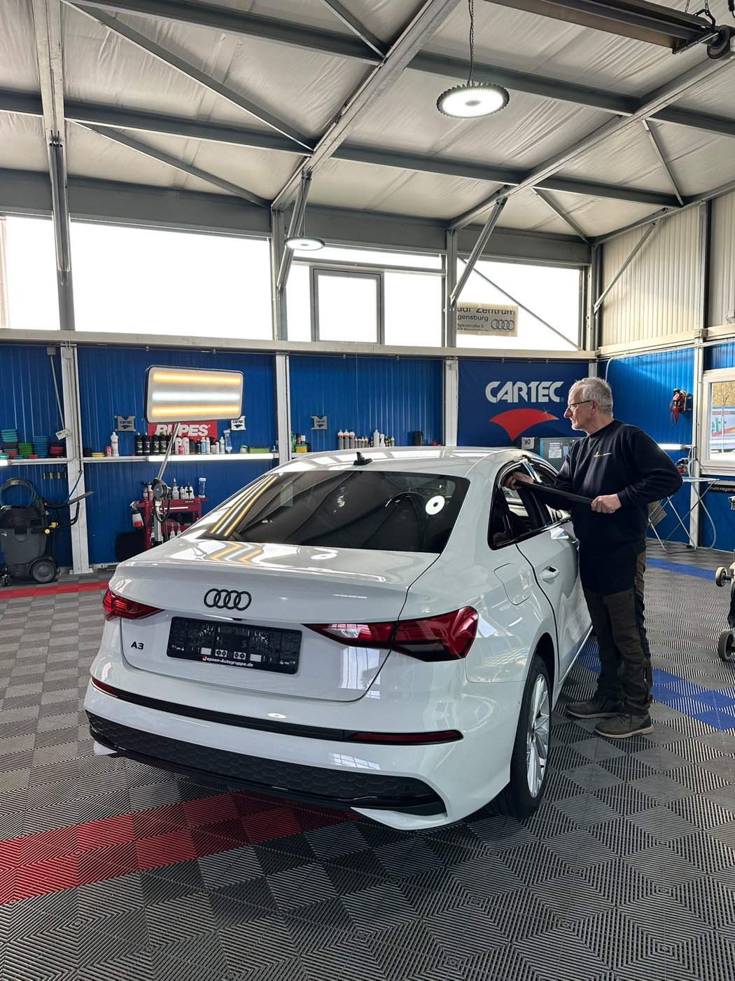 CARTEC-Dellentechniker drückt mit dem Ausbeulhebel Hageldellen am Dach eines weißen Audi A3 heraus