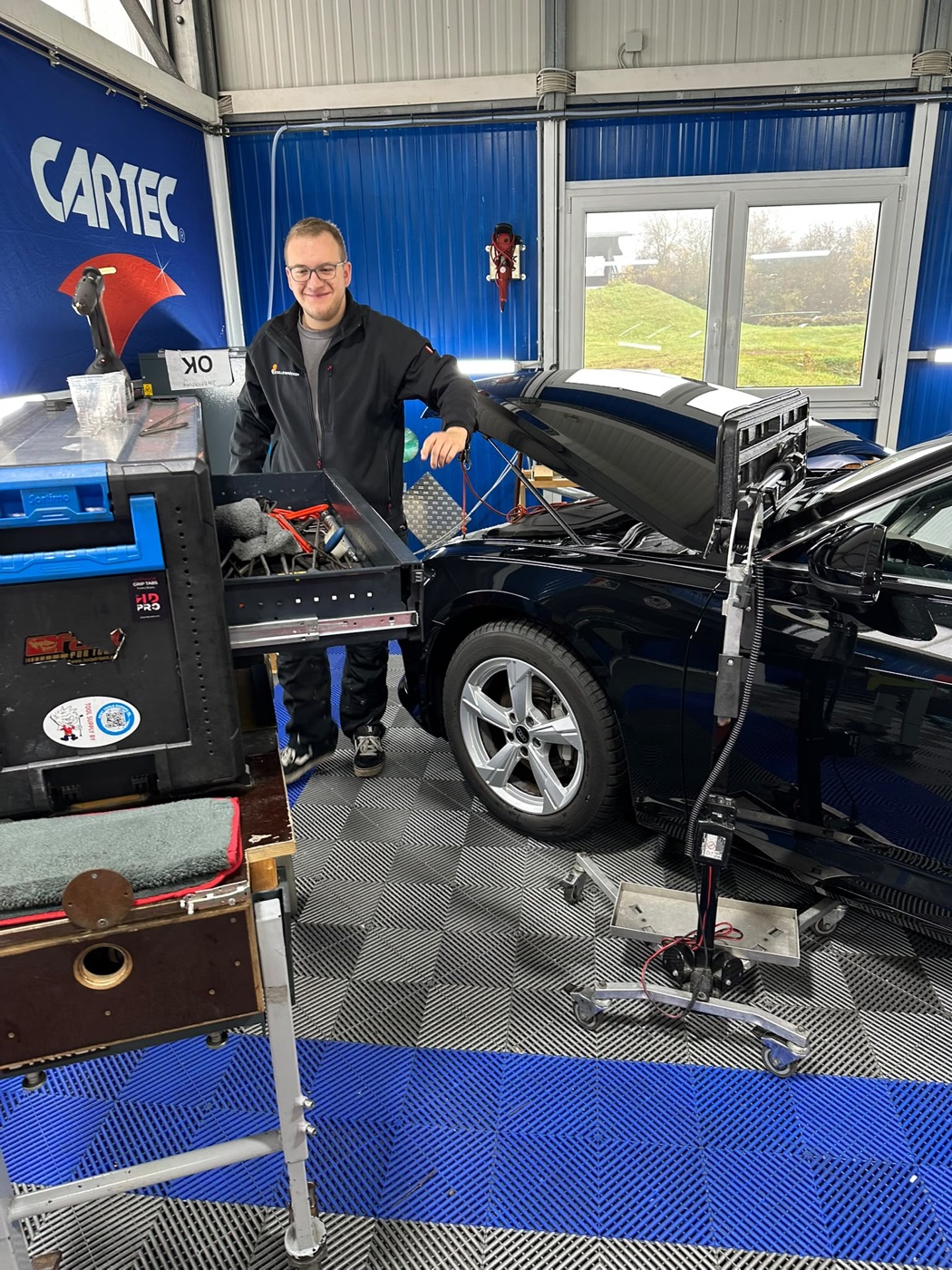 CARTEC-Dellentechniker mit Ausbeulwerkzeug und Dellenlampe an einem schwarzen Audi