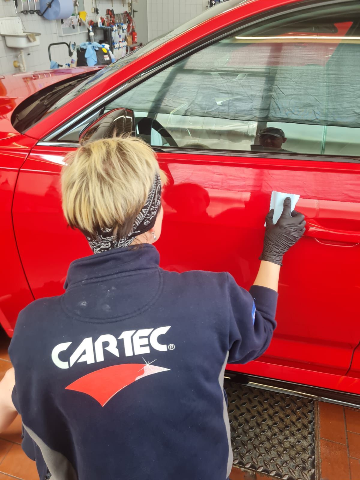 CARTEC-Mitarbeiterin bei der Lackversiegelung eines roten Fahrzeugs